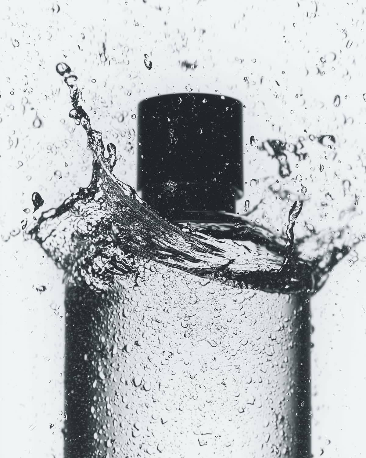 Black-capped cosmetic bottle with water splash