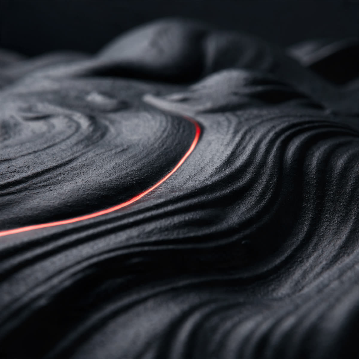 Rippling matte charcoal texture with a red-orange streak of light